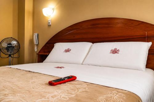 a red remote control sitting on top of a bed at Hotel Zackenbarsch in Huánuco