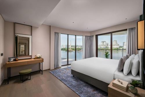 a bedroom with a large bed and a desk and window at Fraser Residence Putrajaya in Putrajaya