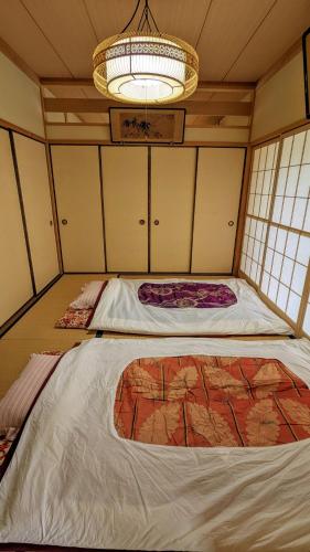 a room with two beds and a chandelier at ゲストハウスヒスイ in Kuchi-sada