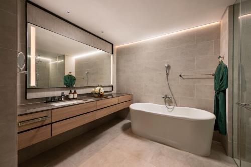 a bathroom with a tub and a sink and a mirror at Fraser Residence Putrajaya in Putrajaya