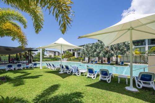 a pool with chairs and umbrellas next to a building at Blue on Blue Apartment 1015 in Nelly Bay
