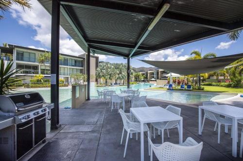 a patio with tables and a grill and a pool at Blue on Blue Apartment 1015 in Nelly Bay