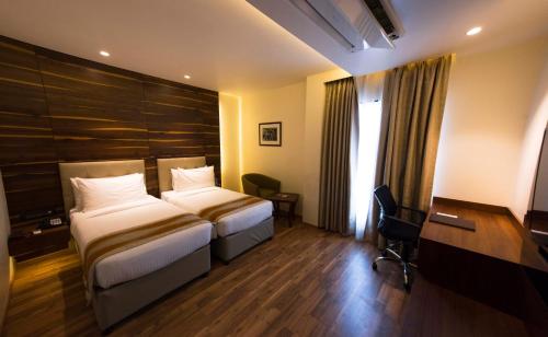 a hotel room with two beds and a desk at Connaught Royale Delhi in New Delhi