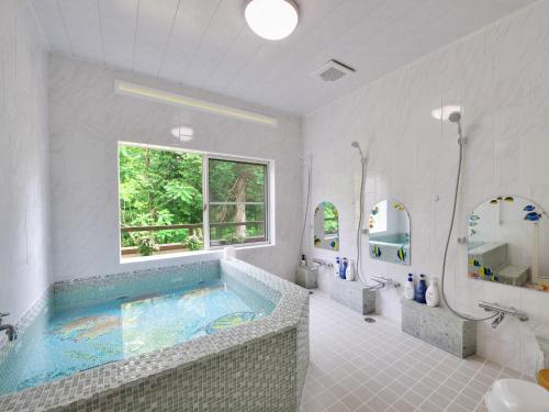 a bathroom with a large tub with a window at Chateau Le Fleur in Ito