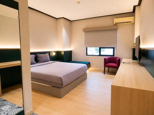 ein Schlafzimmer mit einem Bett und einem roten Stuhl in der Unterkunft Summerday Hotel in Ulin