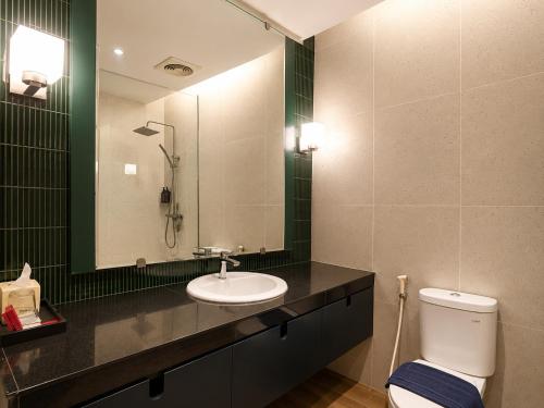 ein Badezimmer mit Waschbecken, Toilette und Spiegel in der Unterkunft Summerday Hotel in Ulin
