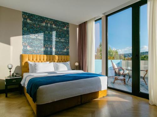 een slaapkamer met een groot bed en een balkon bij Museum Hotel in Tbilisi City