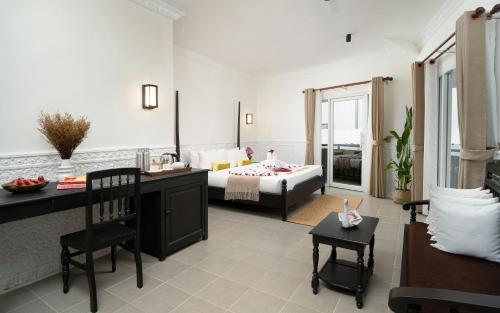a hotel room with a bed and a table and chairs at The Palace Indochine Hotel in Siem Reap