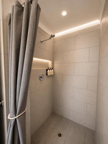 a shower with a gray curtain in a bathroom at The Espiritu in Luganville