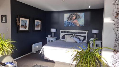 a bedroom with blue walls and a bed with plants at Christchurch - Port Levy, Bed & Breakfast in Port Levy