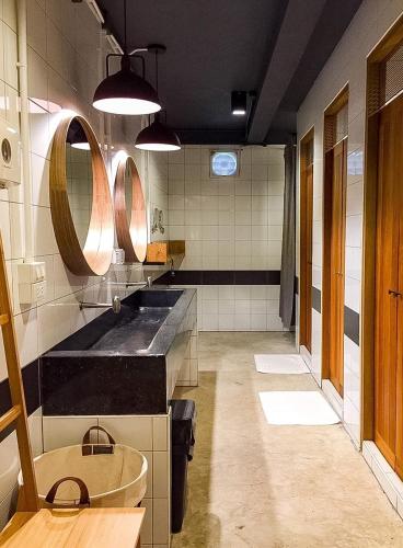 a large bathroom with two sinks and two mirrors at Bedgasm Hostel Chanthaburi in Chanthaburi