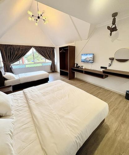a bedroom with a large white bed and a tv at Kea Garden Guest House in Brinchang