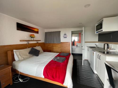 a bedroom with a bed with a red blanket on it at Punakaiki Beach Hostel in Punakaiki