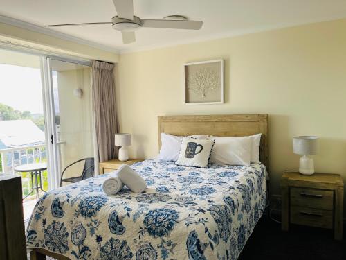 a bedroom with a bed with a blue and white comforter at Horizons At Peregian in Peregian Beach