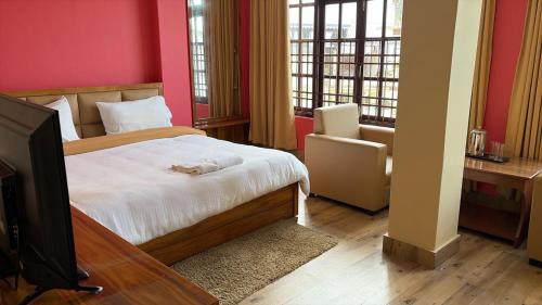 a bedroom with a bed and a tv and windows at Hotel Sai Kripa, sikkim in Ravangla