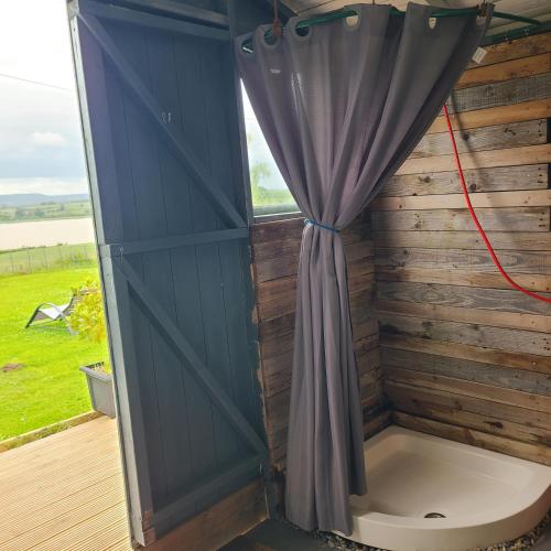 a shower with a curtain next to a window at The Riverside Retreat in Blakeney