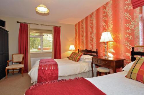 Rowanville Lodge في Grange: غرفة فندقية بسريرين مع ستائر حمراء