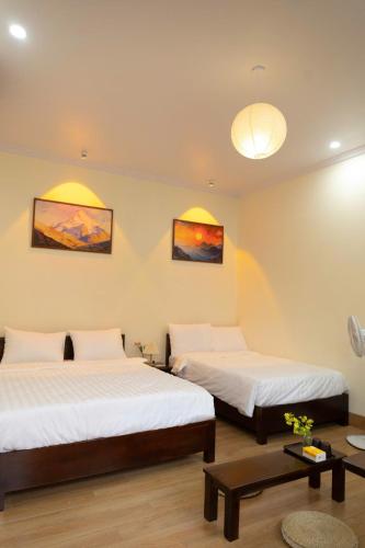 two beds in a room with two tables at Tan Ca Home & Studio Ninh Bình in Kỳ Vĩ