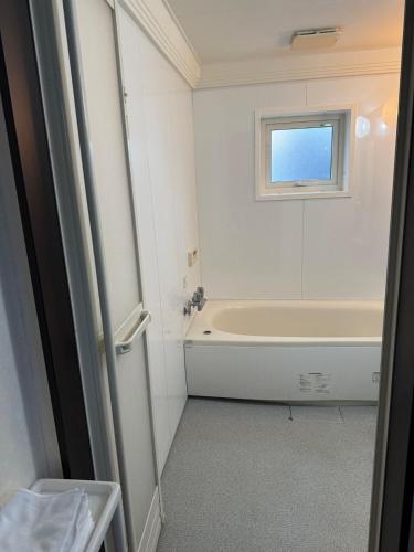 a bathroom with a bath tub and a window at Gold rich 2 in Asahikawa