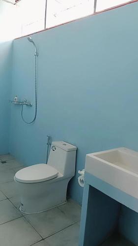 a blue bathroom with a toilet and a sink at Blue Rose Resort & Dive Center in Pattimura Airport