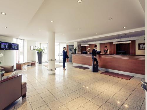 two people standing in a lobby with a counter at Sunday Hotel München Airport Freising in Freising