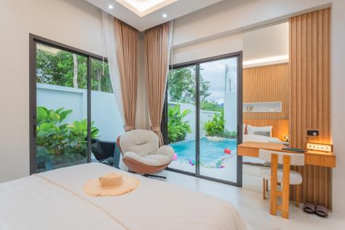 a bedroom with a bed and a desk and a chair at Luxury B Baya Pool Villa in Ban Chong Phli