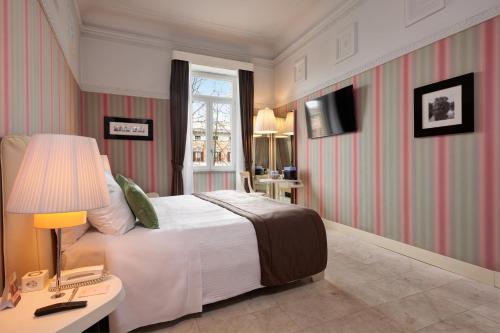a bedroom with a bed and a table with a lamp at Grand Hotel Palace Rome in Rome