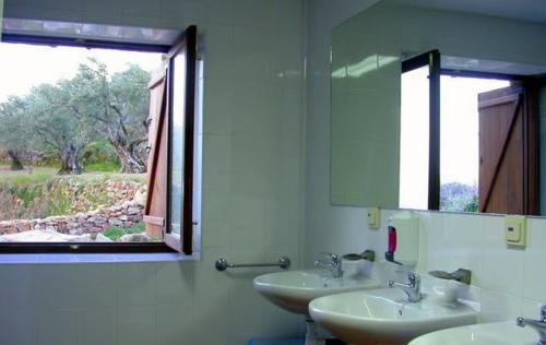 Baño con 2 lavabos, espejo y ventana en Albergue Aurora Boreal, en Casas del Monte