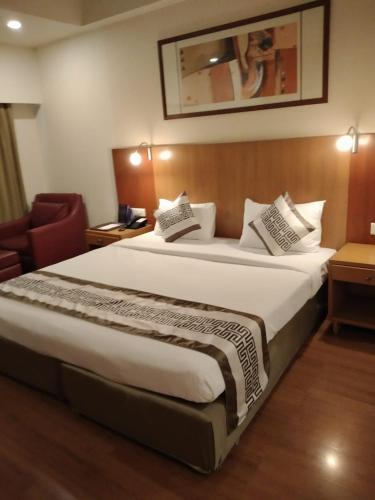 a hotel room with a large bed and a chair at Taj Tristar in Hyderabad