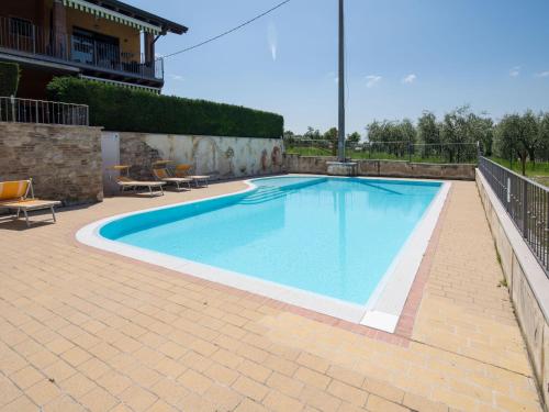 a large swimming pool on a brick patio at Snug Holiday Home in Lazise with Heating, near Lake Garda in Lazise