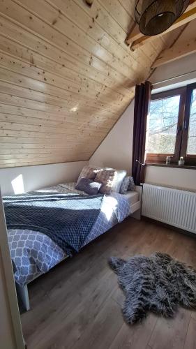 a bedroom with a bed and a wooden ceiling at Bliżej Lasu - Rodzinny domek w górach in Stary Gieraltów