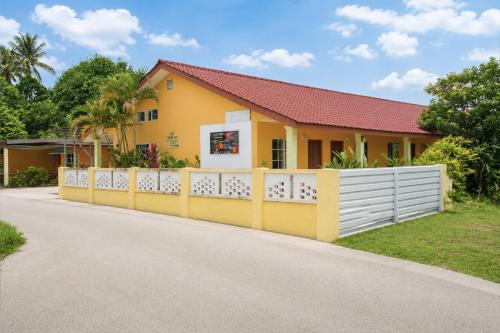 a yellow house with a white fence at Collection O Langkawi Near Pantai Cenang formerly Tokman Inn in Pantai Cenang