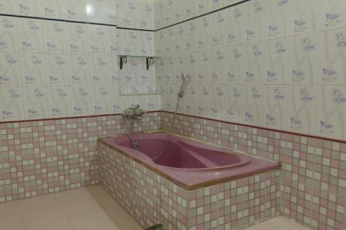 a pink bath tub in a tiled bathroom at Ghotul Hostel & Homestay in Guwahati
