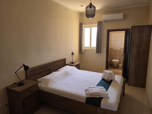 a bedroom with a large bed and a bathroom at Salty Sun Seafront Penthouse in Marsalforn