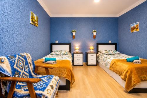 two beds in a room with blue walls at Guest house poligloti in Telavi