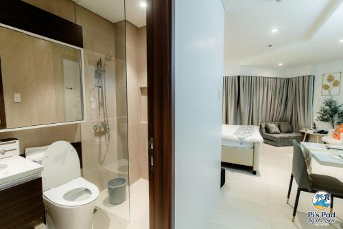 a bathroom with a toilet and a sink and a bedroom at Tambuli Seaside Living Pad seaview in Maribago