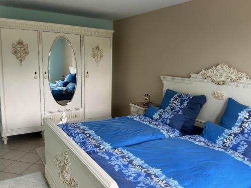 a bedroom with a bed with blue sheets and a mirror at Zur Kapellenwiese in Oberthal