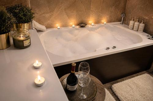 a bath tub with candles and wine bottles and wine glasses at Galaxy Apartments in Belgrade