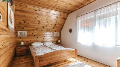 a bedroom with a bed and a wooden wall at Domki na Olszynki in Okuninka