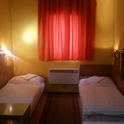 a room with two beds and a red curtain at Kis-Duna Motel & Camping in Mosonmagyaróvár