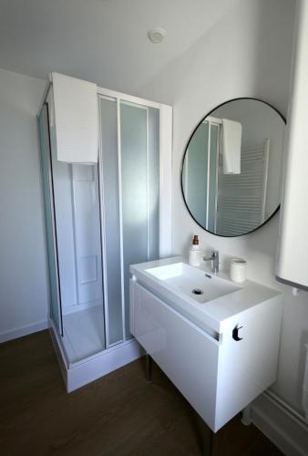 a white bathroom with a sink and a mirror at Cozy Apartment in Pontgibaud