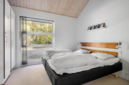 a bedroom with a bed with white sheets and a window at 6715-Hasle-Skovkanten-12 in Hasle