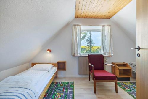 a bedroom with a bed and a chair and a window at 9116-Gudhjem-Rovej-22 in Gudhjem