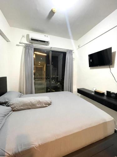 a bedroom with a bed and a flat screen tv at APARTEMEN SKY HOUSE BSD in Samporo