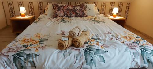 a bed with towels on it with two night stands at Villa VértesKacsa in Vértesacsa