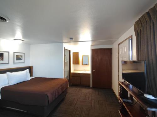 a hotel room with a bed and a flat screen tv at Neva Jean Motel in Marshfield