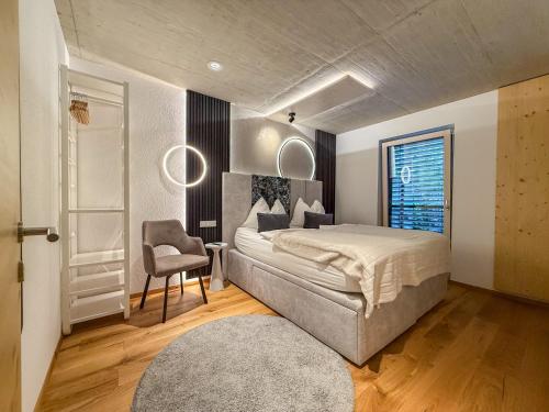 a bedroom with a large bed and a chair at Mid Mountain Apartment Tirol in Wiesing