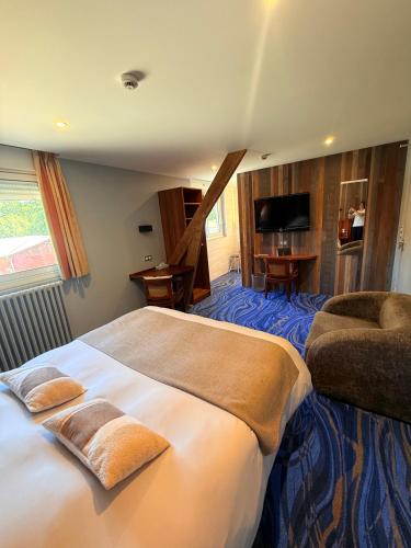 a hotel room with a large bed and a chair at Hôtel Roc Land in Val Couesnon