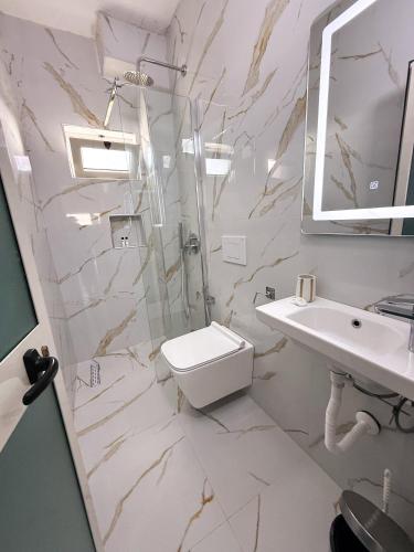 a bathroom with a toilet and a sink and a shower at Willy Apartments in Velipojë
