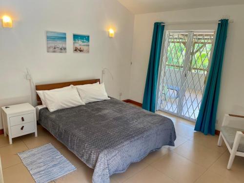 a bedroom with a bed and a window with blue curtains at La Casa Margot in Albion
